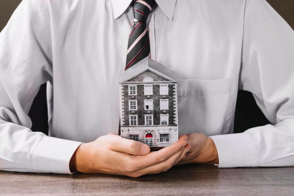 man-holding-miniature-house-hands